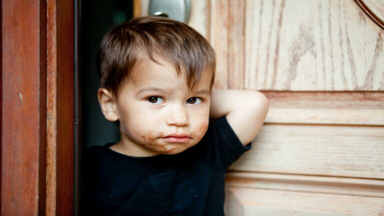 Child standing near a wooden door