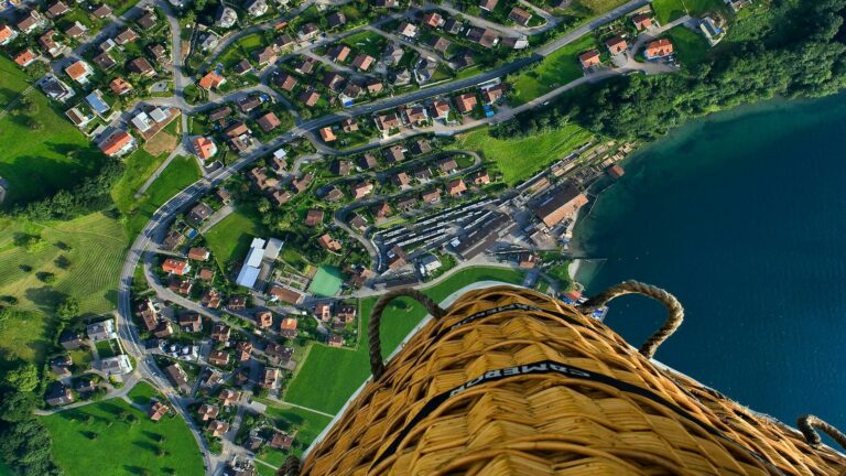 A view from a hot air balloon showing a residential area near a lake.