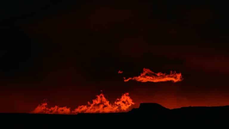 Silhouette of a landscape with red flames against a dark sky