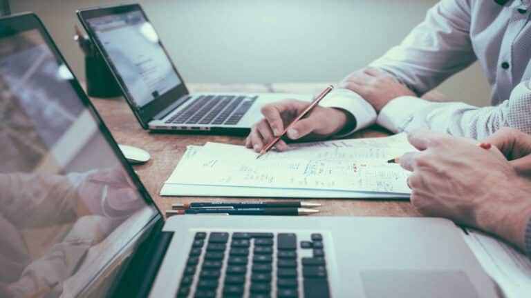 Two people working on a business plan with laptops