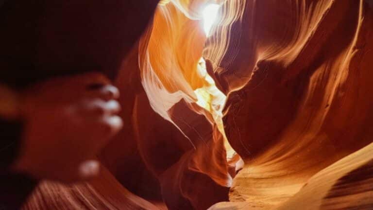 Natural sunbeam illuminating smooth sandstone walls in Antelope Canyon, creating dramatic orange and red tones