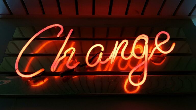 Glowing red neon sign displaying the word 'Change' mounted on a dark wall