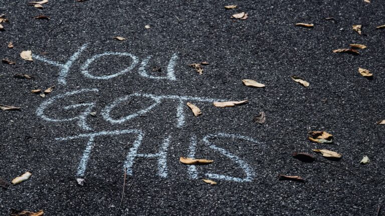 Chalk writing on asphalt surface showing 'You Get Time' message with scattered leaves