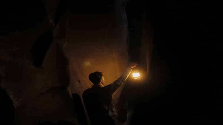 Person holding a lantern in a dimly lit cave, showcasing the importance of Local SEO techniques for visibility