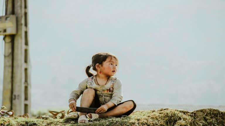 Young child sitting on grass holding an object, symbolizing focus and creativity in website performance analysis.