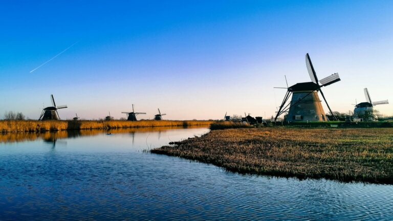 Scenic landscape of historic windmills along a waterway in Netherlands during golden hour