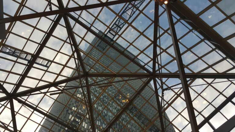 Looking up through geometric glass ceiling structure at modern skyscraper building