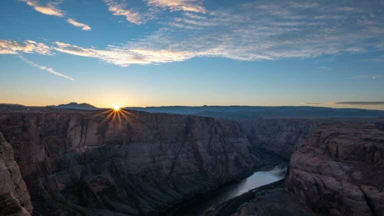 Sunrise casting light over a canyon with a river flowing through it