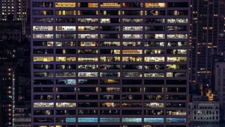 Night view of a lit office building with multiple floors visible