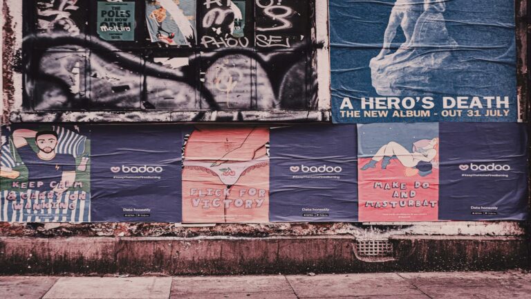 A wall covered with various posters, including advertisements and graffiti.