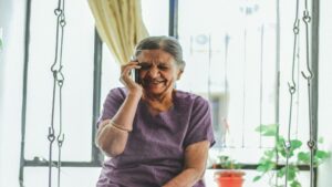 Elderly woman sitting on a swing and talking on a mobile phone to improve communication