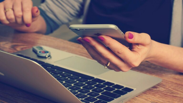 Person using a smartphone and laptop at a web design agency in London