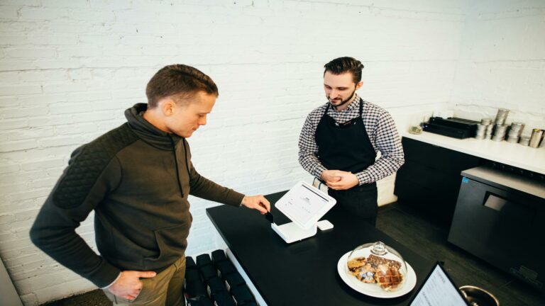 Customer making a payment at a cafe using a digital point-of-sale system, showcasing mobile website optimization benefits.