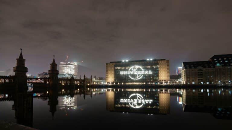 Universal building in Berlin at night reflecting on the river, showcasing modern architecture and iconic landmarks