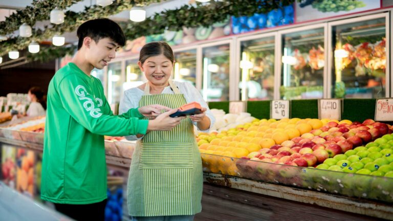 Customer and vendor interacting at a fruit market, showcasing vibrant produce and a digital payment device.