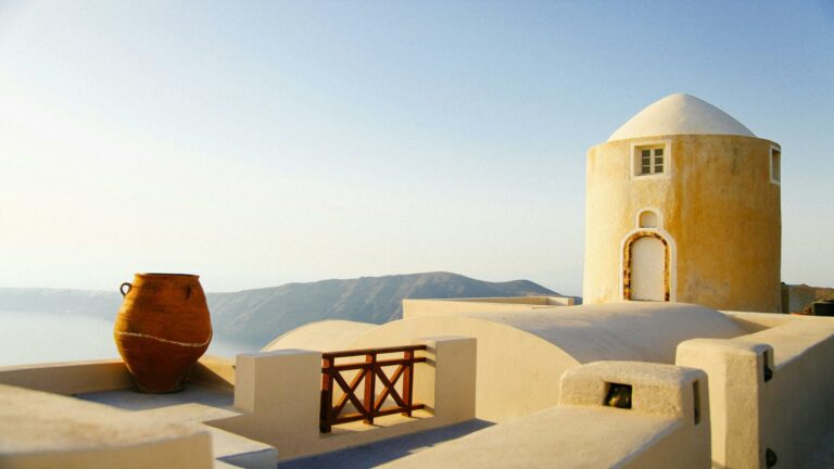 Traditional Santorini architecture with a yellow dome building and terracotta pot overlooking the Aegean Sea - Search Engine Optimization