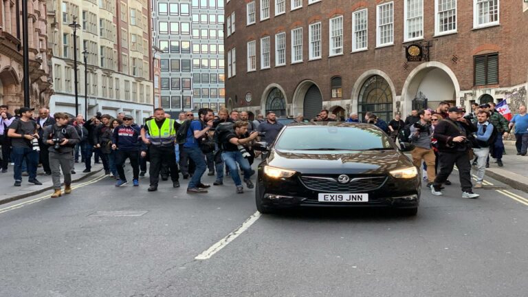 Website optimization services demonstration with crowd of photographers outside brick building in London