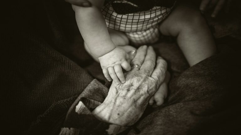 A touching moment of a baby holding an elderly hand, symbolizing generational connection and site usability improvement.