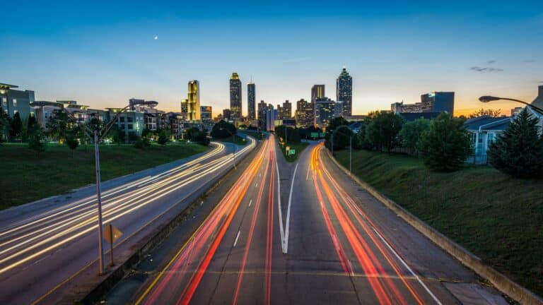 Atlanta cityscape with light trails from vehicles on the highway, showcasing vibrant urban life and modern architecture.