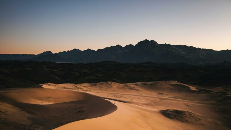 Desert dunes with a silhouette of mountains in the background at dusk, captured by Web Design London