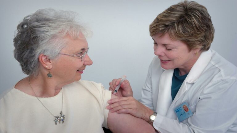 Healthcare professional giving a vaccine to an elderly woman - Website design company