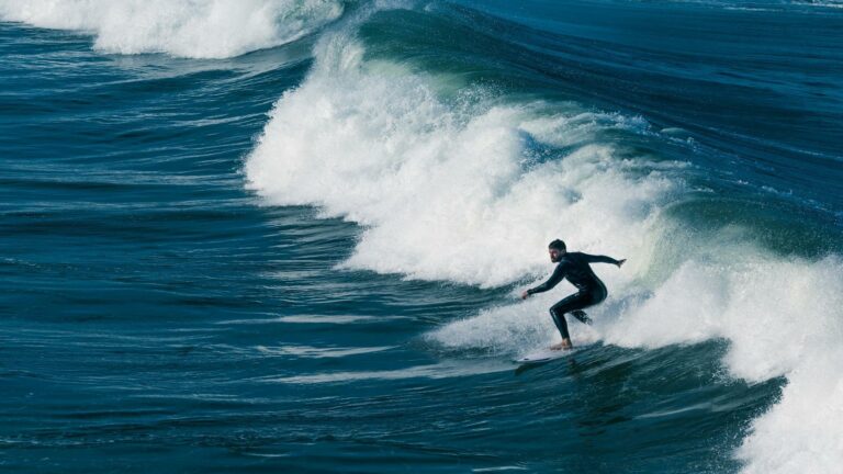 Surfer riding a large wave in the ocean, showcasing balance and skill