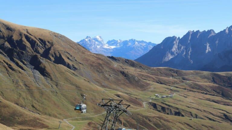 Cable car crossing scenic alpine valleys with snow-capped mountains in the background