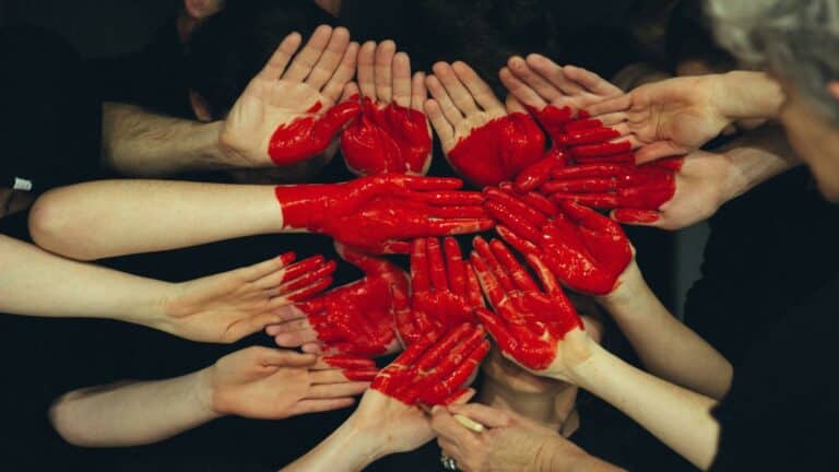 Collaborative hands painted red forming a heart shape, symbolizing teamwork and creativity in web design and digital marketing.