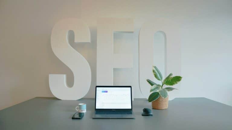 Laptop on a desk with SEO letters in the background, symbolizing effective social media for SEO