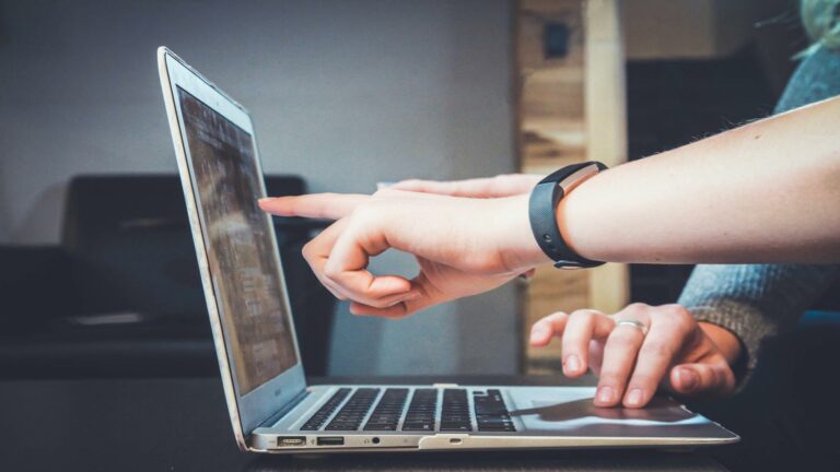 Content marketing professional using laptop with fitness tracker, demonstrating modern digital workplace strategy