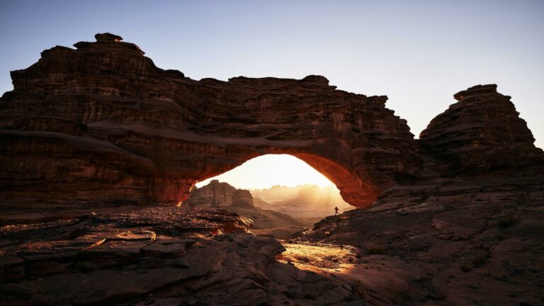 Rock arch in a desert landscape with sunlight streaming through, symbolizing natural beauty and resilience