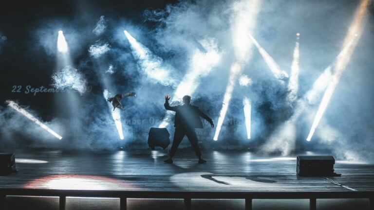 Silhouette of a performer on stage with dramatic lighting and smoke effects, representing local marketing campaigns