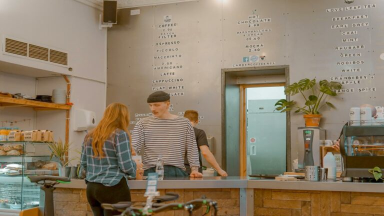 Coffee shop counter with customers ordering, showcasing a menu board and cozy design in a London cafe