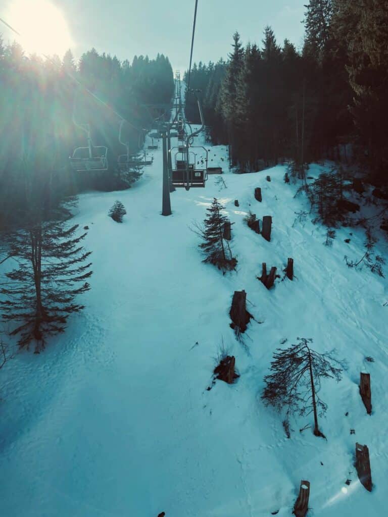 Ski resort chairlift traversing snowy slopes surrounded by evergreen forest, showcasing outdoor recreation design business in winter tourism