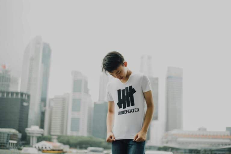 Young design business professional wearing Undefeated t-shirt against foggy urban skyline