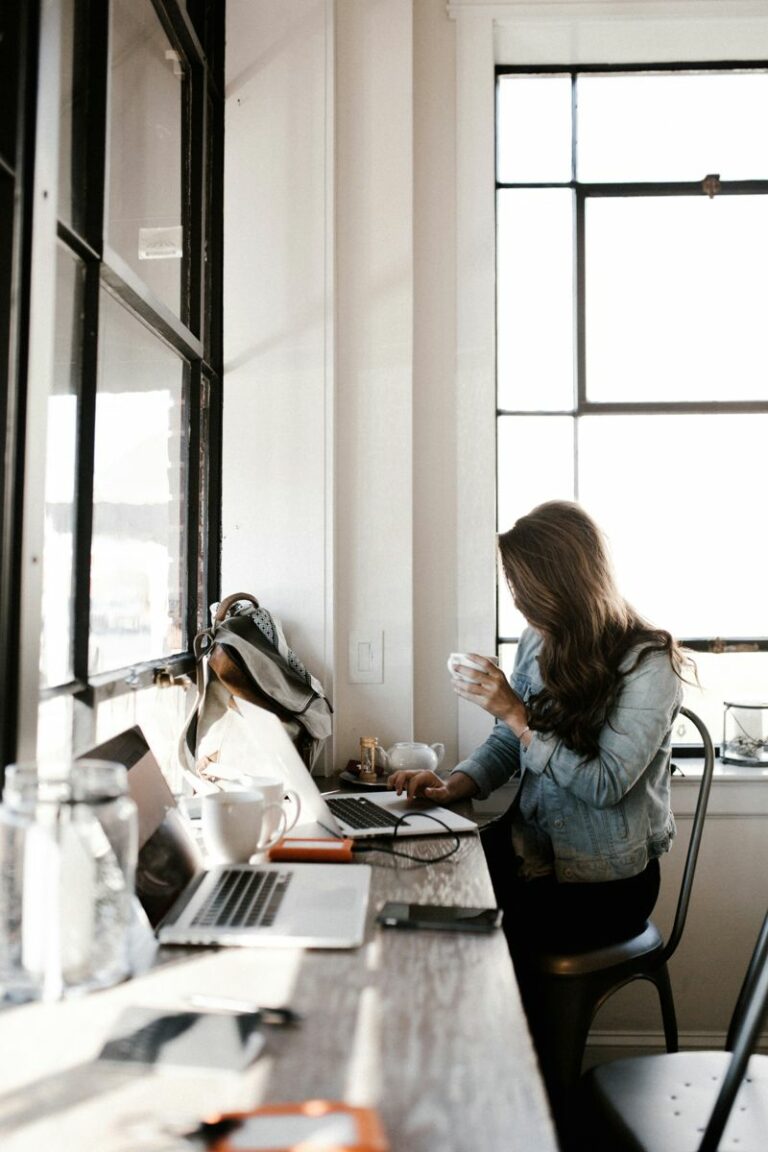 Professional in design business working on laptop in bright minimalist workspace with coffee